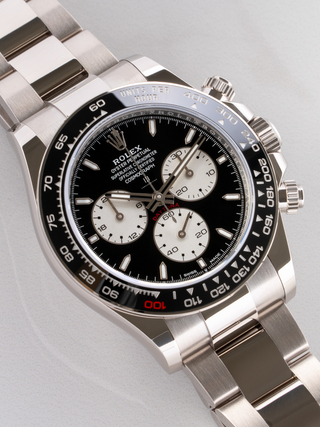 Diagonal  view of a Rolex Daytona, showcasing the stainless steel case and bracelet, the white subdials with black outlines