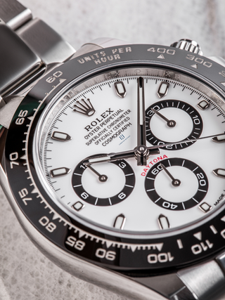 Close-up of the dial of a Rolex Daytona (Panda dial), highlighting the tachymeter scale on the bezel, the contrasting black subdials with the Rolex coronet logo