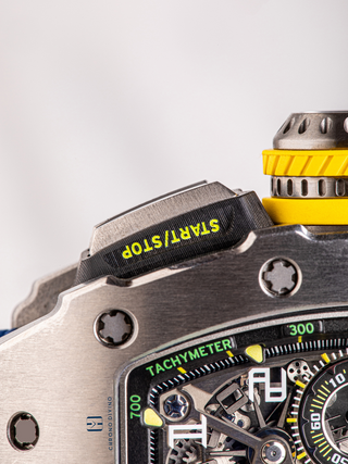 The start/stop button and a part of the dial of Richard Mille RM11-03Ti is visible with the letter tachymeter