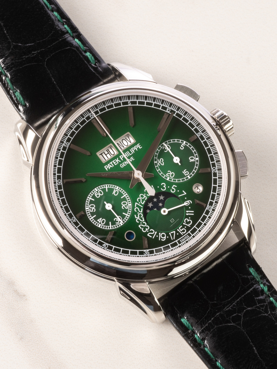 Patek Philippe 5270P-014 is in the picture with platinum case, green lacquered dial, chronograph, and black alligator strap