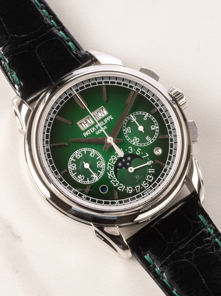 Patek Philippe 5270P-014 is in the picture with platinum case, green lacquered dial, chronograph, and black alligator strap