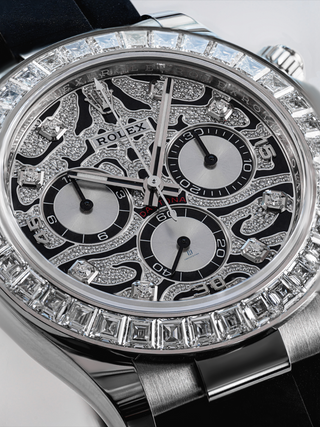 Close-up of the dial of a Rolex Daytona watch, highlighting the intricate diamond setting, the contrasting black subdials with diamond outlines