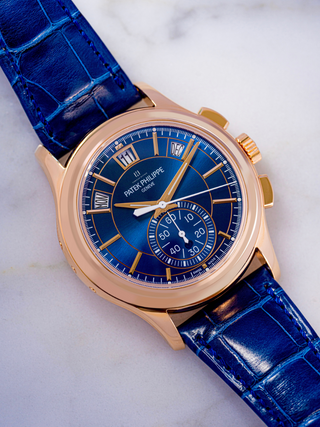 The image is Patek Philippe 5905R-010 in rose gold with a sunburst blue dial, flyback chronograph, and blue strap