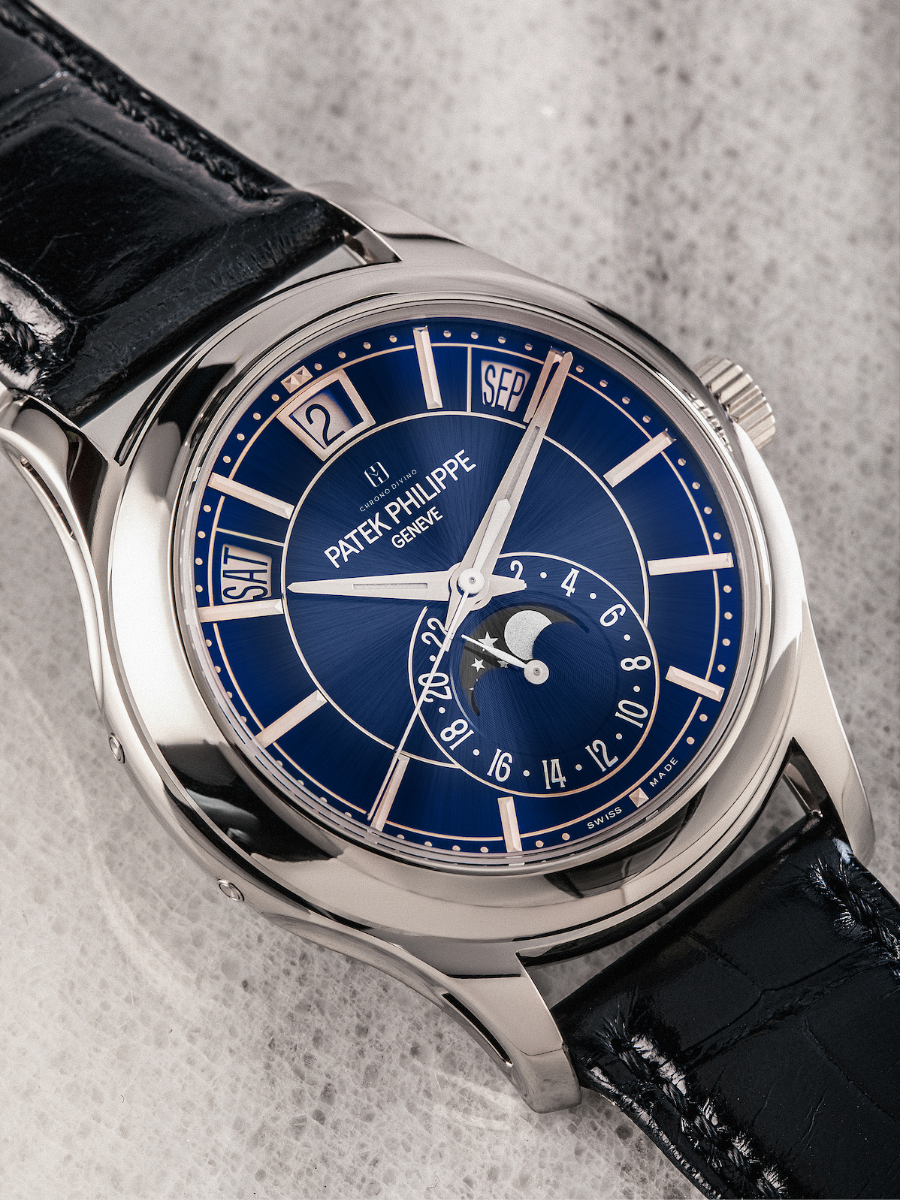 The image presents Patek Philippe 5205G-013 White Gold Watch with a Calendar, Moon Phase, Blue Sunburst Dial, and Strap
