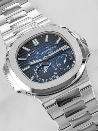 A silver Patek Philippe 5712/1A placed diagonally focusing on the blue dial