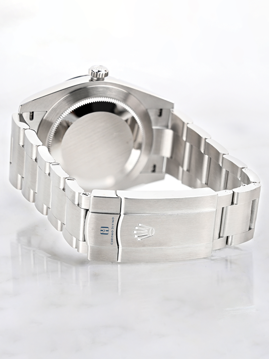 Stainless steel Rolex watch with visible case back, bracelet, clasp, and engravings, resting on a light surface