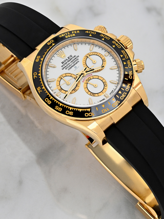 Yelllow Gold Rolex Daytona 126518LN on a marble background showcasing dial details, complications, bezel, and angled composition