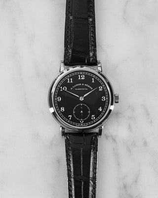 A. Lange & Söhne 1815 200th Anniversary edition with black dial, platinum case, and small seconds subdial – laid flat on marble surface.