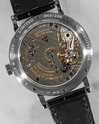 Top-down image of A. Lange & Söhne limited-edition 1815 in platinum with black dial and leather strap – minimalist design on stone background.