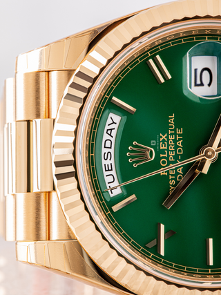 Rolex Oyster Perpetual Day-Date watch in gold, featuring a fluted bezel, a green dial with gold stick hour markers