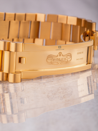 Gold Rolex bracelet with clasp, visible branding, and reflection on surface