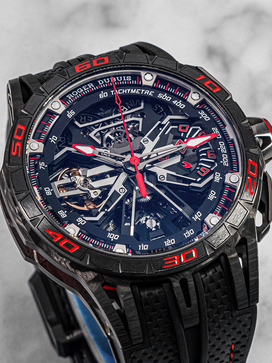 Roger Dubuis Excalibur Spider Flyback Chronograph in titanium with skeleton dial, red accents, and black rubber strap; front angle view on white background.