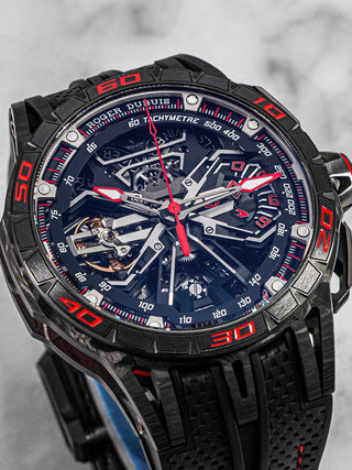 Roger Dubuis Excalibur Spider Flyback Chronograph in titanium with skeleton dial, red accents, and black rubber strap; front angle view on white background.